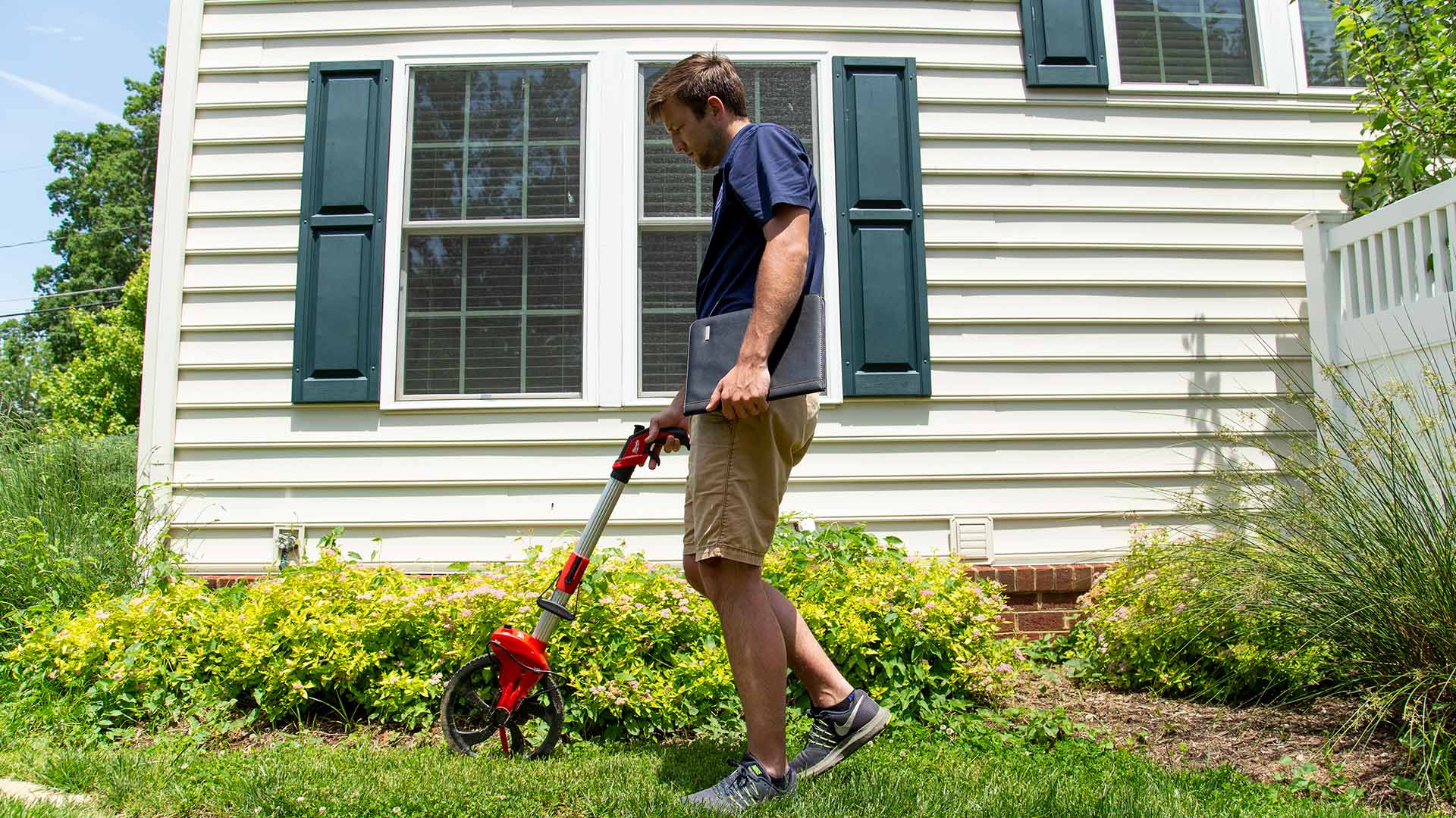 A man is measuring a landscape bed to produce the best renovation work possible.
