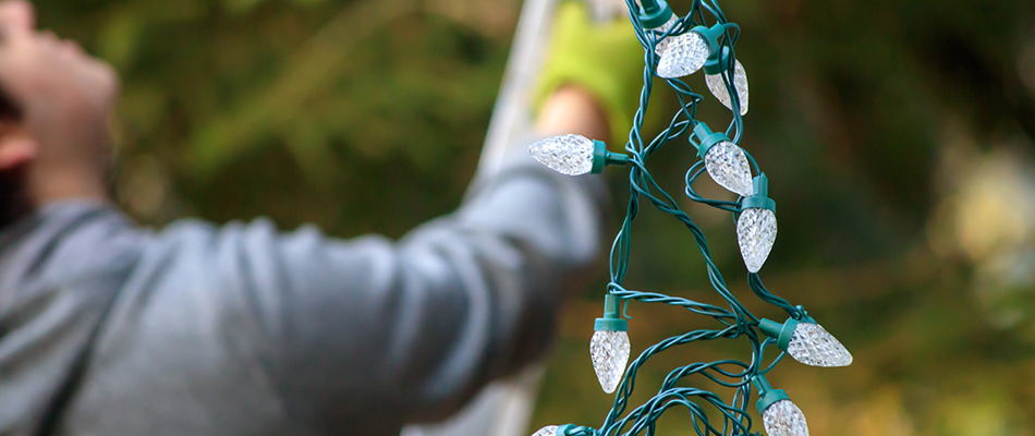 A professional is installing holiday lighting for a client near Arlington, VA.