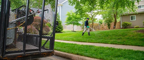 A professional is spraying lawn fertilizer over a lawn.