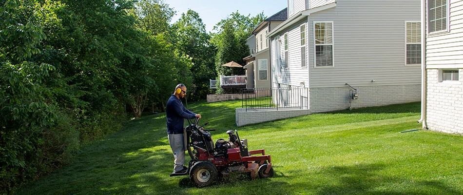 Hambleton worker mowing a back yard lawn.