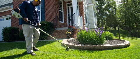 Professional weed whacking around a landscape bed in Potomac Falls, VA.