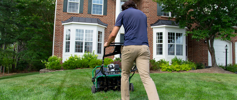 Hambleton Lawn & Landscape lawn care worker aerating a home's lawn in Sterling, VA.