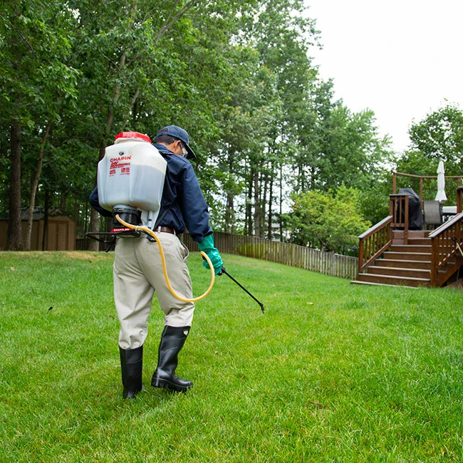Man walking through lawn spraying weed control near Arlington, VA.