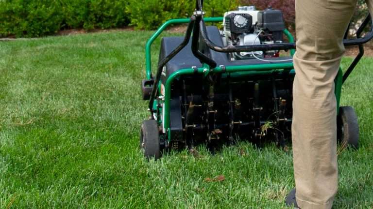 Hambleton worker pushing core aerator across lawn
